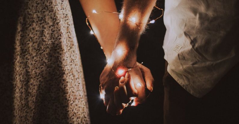 Couple - Man and Woman Holding Each Others Hand Wrapped With String Lights